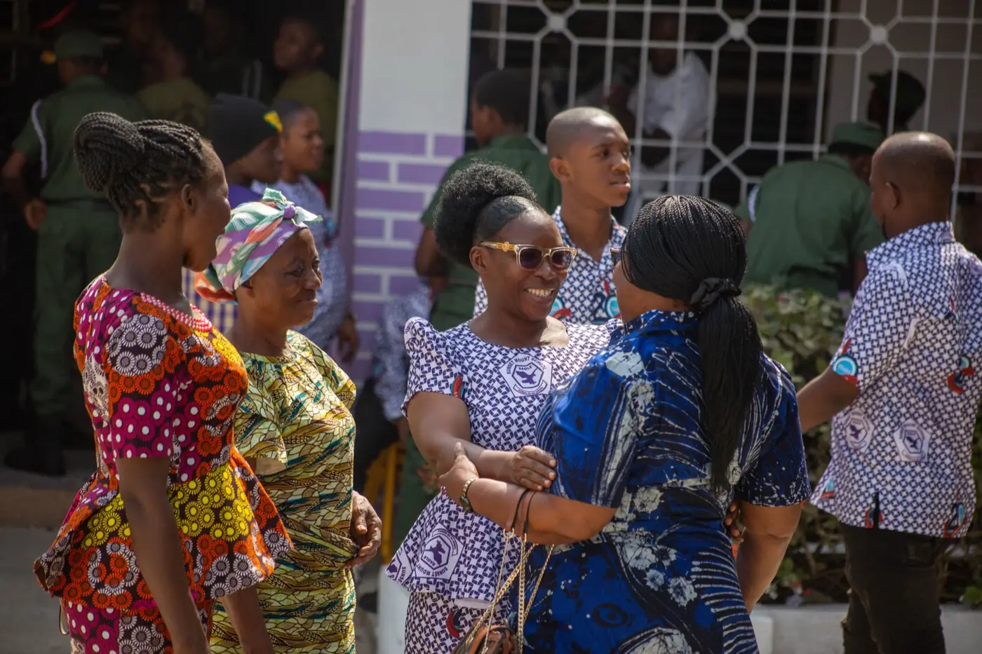 Parents and family members in Ghanaian print cloth greeting one another at a school gathering